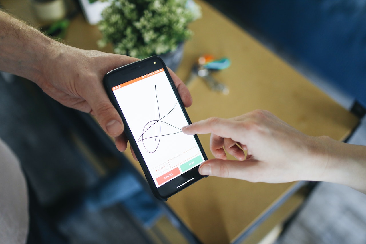 Two hands with a smartphone with an electronic signature