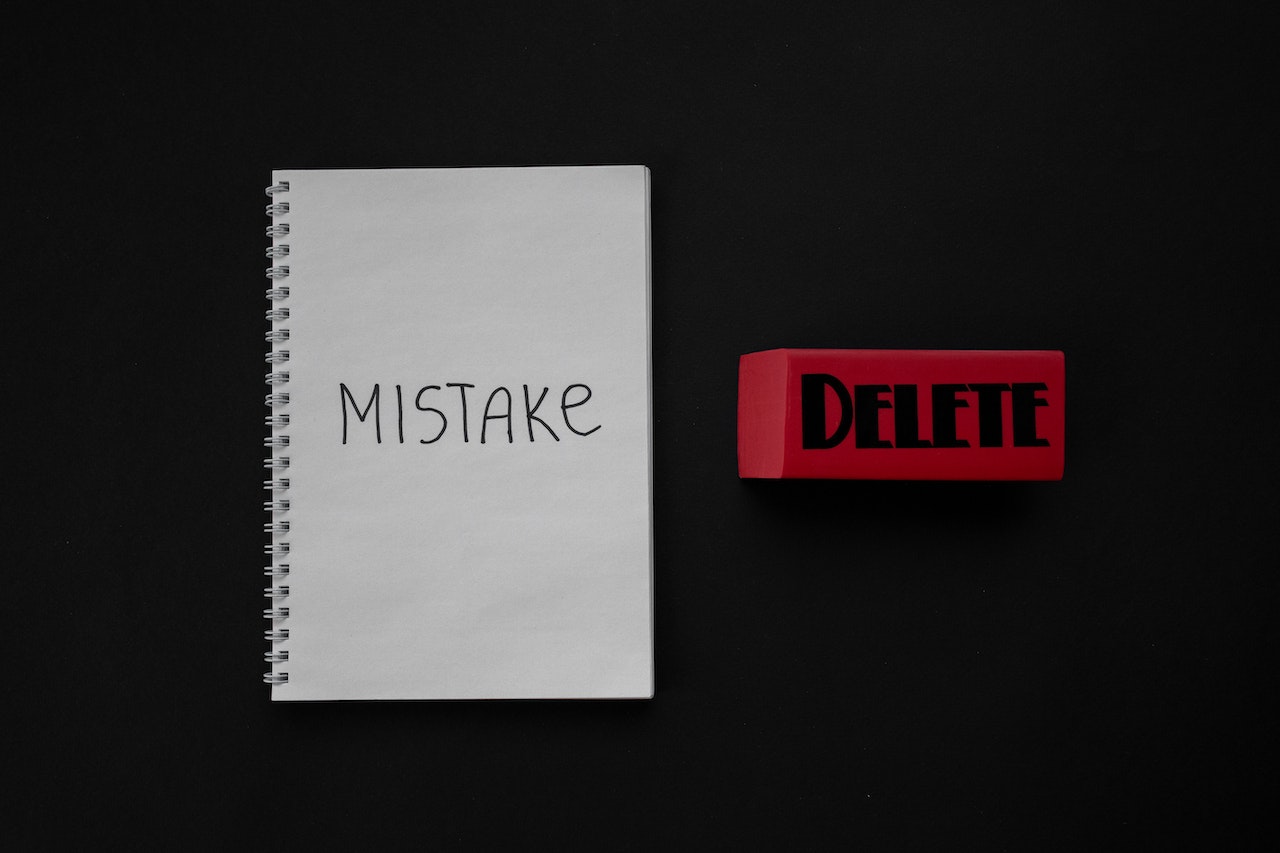 Notebook with a word "Mistake" and a Red button with a word "Delete"