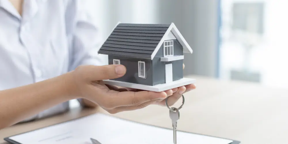 The real estate agent holds the keys and the layout of the house in his hands