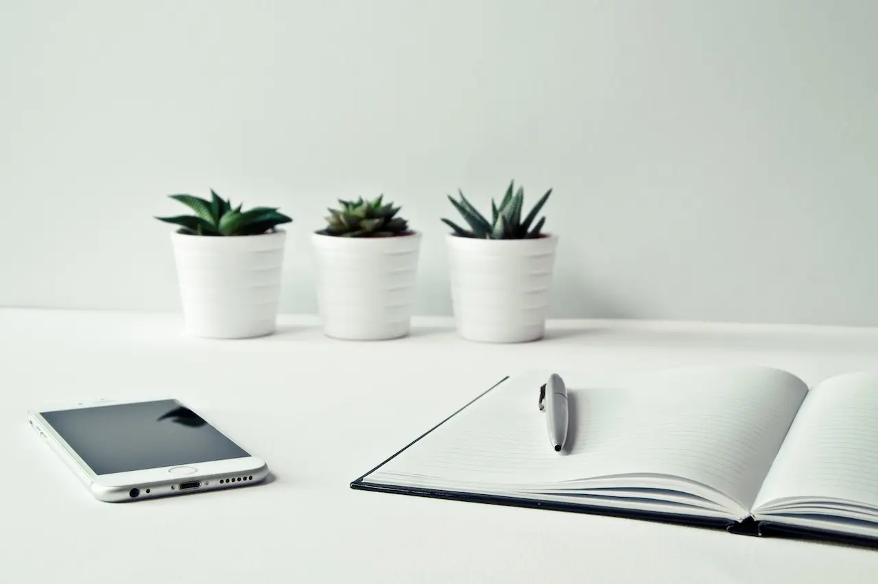 work table with plants, notebook and a smartphone